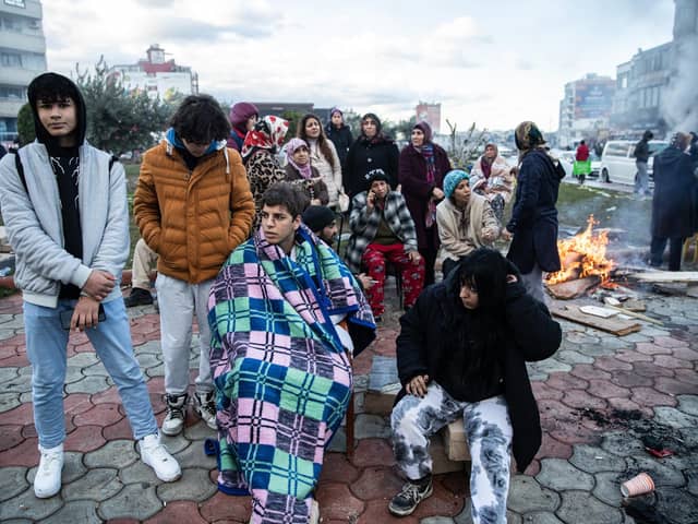 Earthquake survivors sit around a fire in Iskenderun Turkey