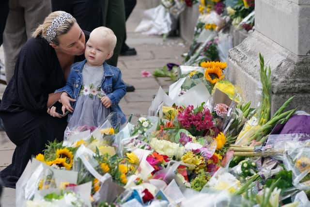 A woman kisses a small child as they look at the flowers laid outside Buckingham Palace, London, following the death of Queen Elizabeth II on Thursday. Picture date: Friday September 9, 2022.