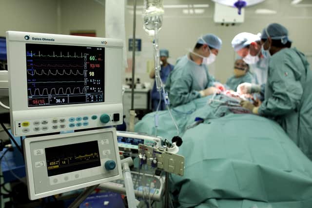 Surgeons carry out an operation to remove a tumour from a patient at an NHS hospital.