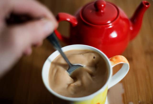 A cup of tea with milk is stirred.
