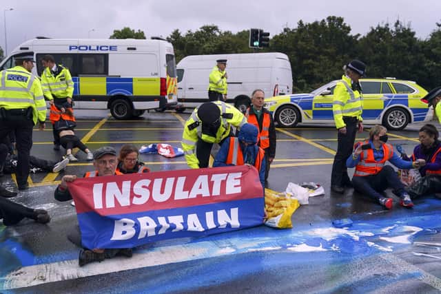 Police officers detain a protester from Insulate Britain occupying a roundabout leading from the M25 motorway to Heathrow Airport in London. Picture date: Monday September 27, 2021. Photo: Steve Parsons/PA Wire