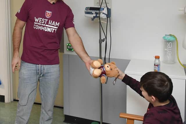 Niclas Füllkrug passes a gift to a young fan at King George's Hospital