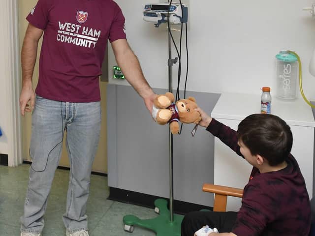 Niclas Füllkrug passes a gift to a young fan at King George's Hospital