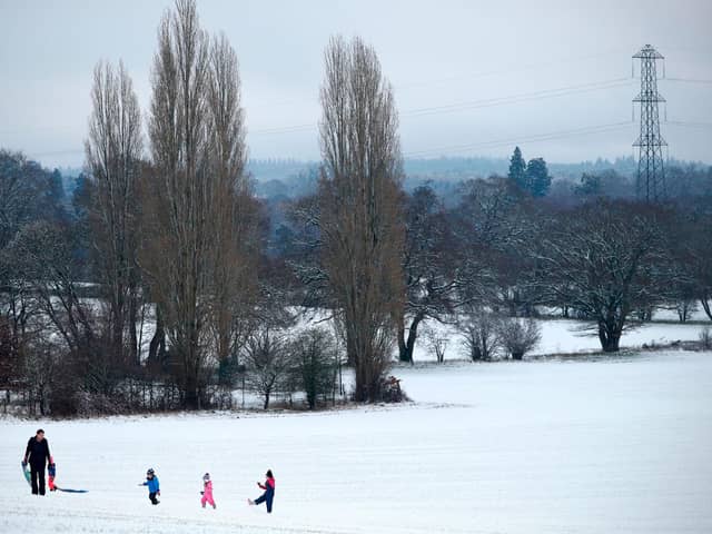 Family play on snow covered hill.